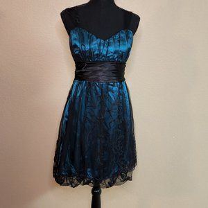 Dark green, sleeveless dress with black lace detail.